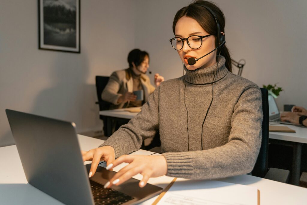 Two call center agents providing customer service in a modern office environment.